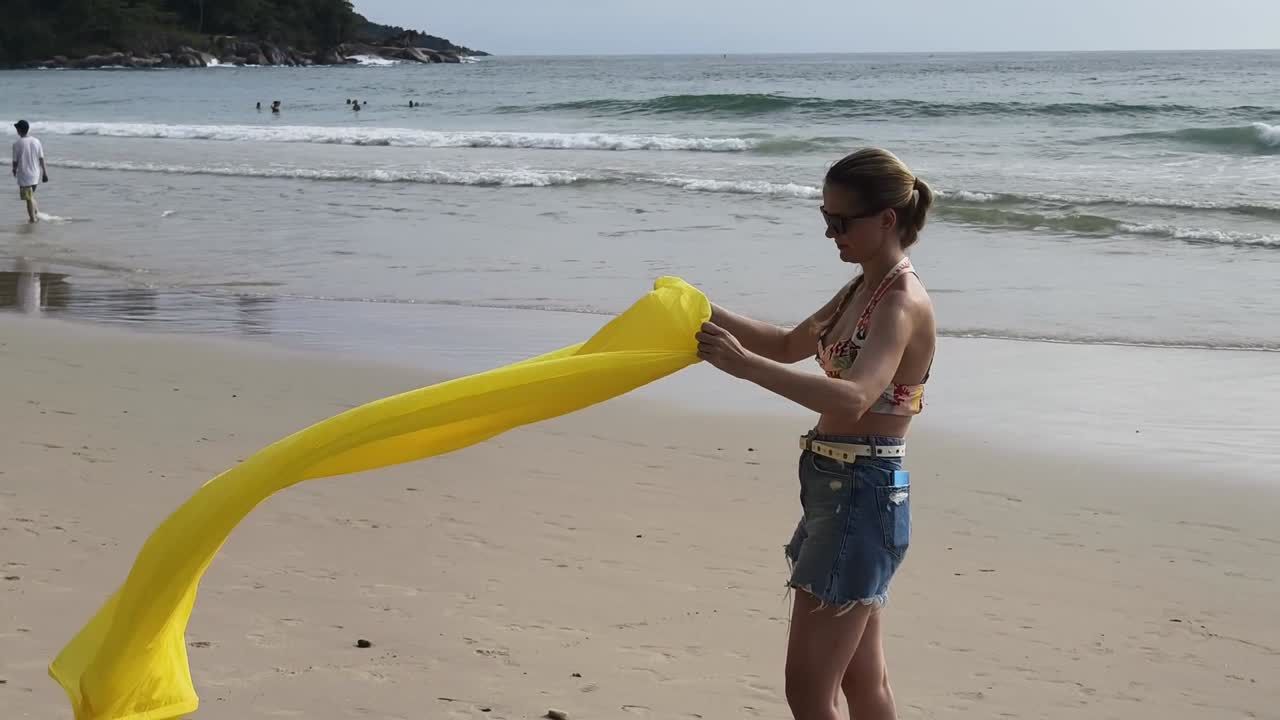 mujer en la playa con tela amarilla