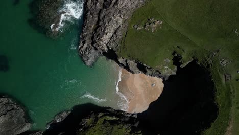 Cala-De-Playa-En-Cornualles-Aislada-Por-Acantilados-Rocosos-Desde-Una-Vista-Aérea-De-Drones-De-Arriba-Hacia-Abajo-Girando-Mientras-Desciende