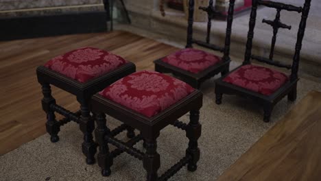 ornate wooden stools with red upholstered seats in a church setting