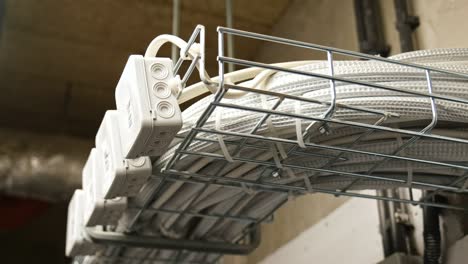 electrical box power cables and telecommunication wiring tied in basket hanging under ceiling in residential building basement