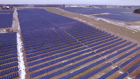 Wide-aerial-pan-of-rows-of-dark-panels-at-huge-solar-power-park-in-USA