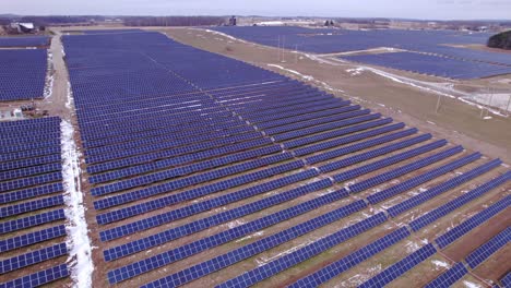 wide aerial pan of rows of dark panels at huge solar power park in usa