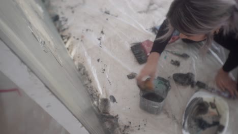 young female artist using sponge to paint lower part of canvas then used a brush