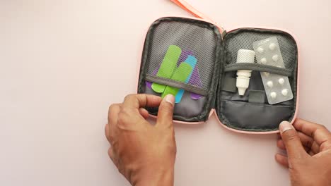 person holding a small first-aid kit with pills and bandages