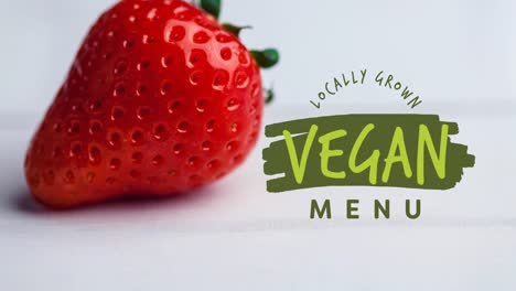 Animation-of-vegan-menu-text-in-green-over-fresh-organic-strawberry