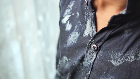 close-up of a man buttoning a patterned shirt