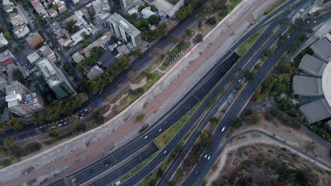 aerial top down dolly in of mapocho river and cars driving in avenues and highway and santiago city neighborhood buildings, chile