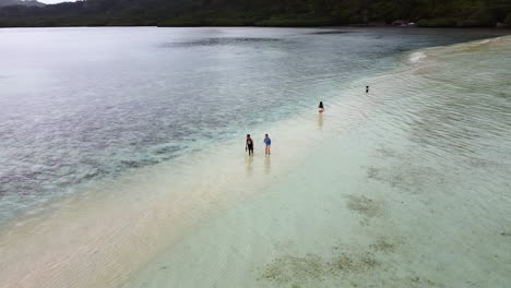 orbit shot over tourists enjoying clear island water on marvelous sand bar