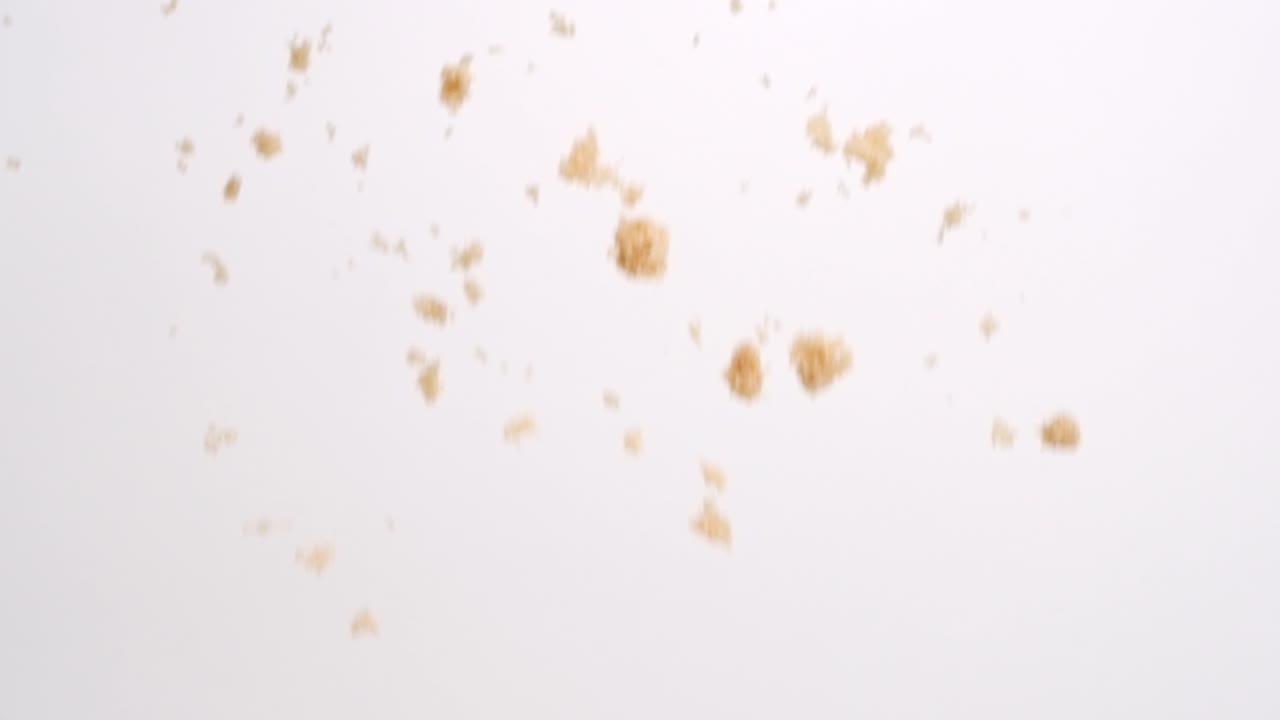 grumi di zucchero di canna che cadono al rallentatore su sfondo bianco studio in 4k