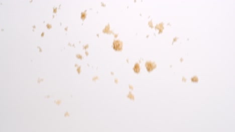 brown sugar clumps falling in slow motion on white studio backdrop in 4k