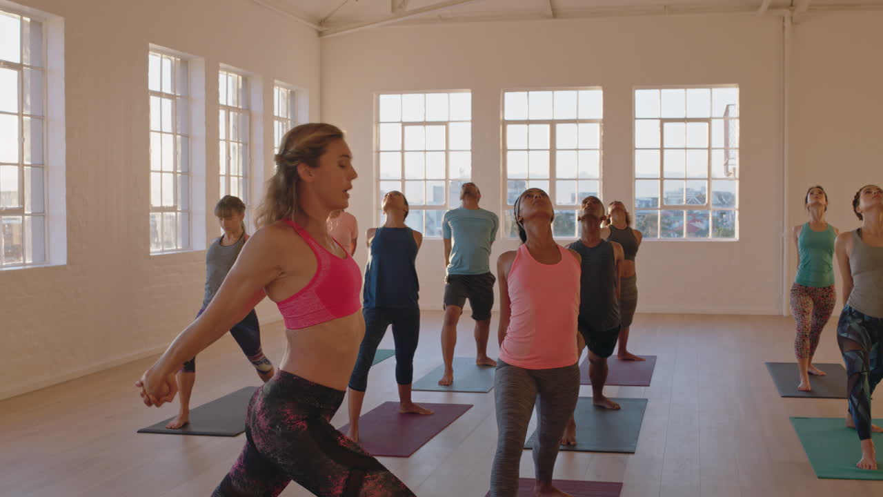 clase de yoga de jóvenes sanos que practican poses estirando el cuerpo disfrutando del ejercicio en el gimnasio con un instructor al amanecer