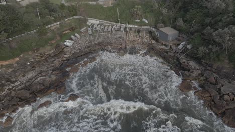 olas salpicando en la bahía de gordon - botes pequeños en la costa en coogee, nueva gales del sur - drone aéreo, retroceso