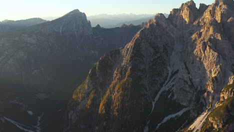 cinematic tilting up drone shot of tre cime di lavaredo a mountain range in italy, with the sun setting