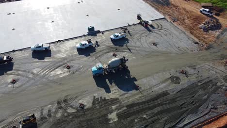 a concrete mixing truck drives across a construction site with a drying concrete pad