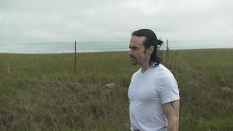 man walking on dirt road by expansive fields