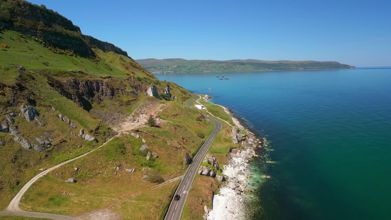 Advancing aerial video of the Causeway Coastal Route at Glenarm in County Antrim, Northern Ireland, UK on a bright and sunny day. Filmed in 4K, 60FPS and with Rec709 color.