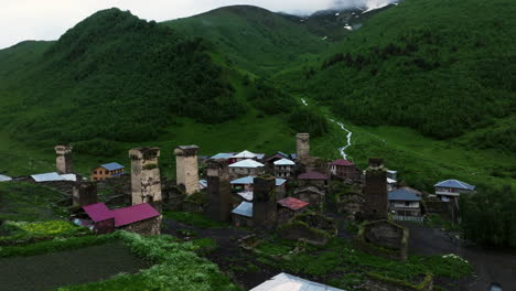 rock towers and old houses in ushguli settlement with lush valley in svaneti, georgia