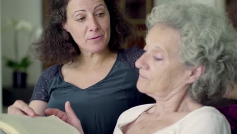 daughter and mother reading book, turning over page, talking