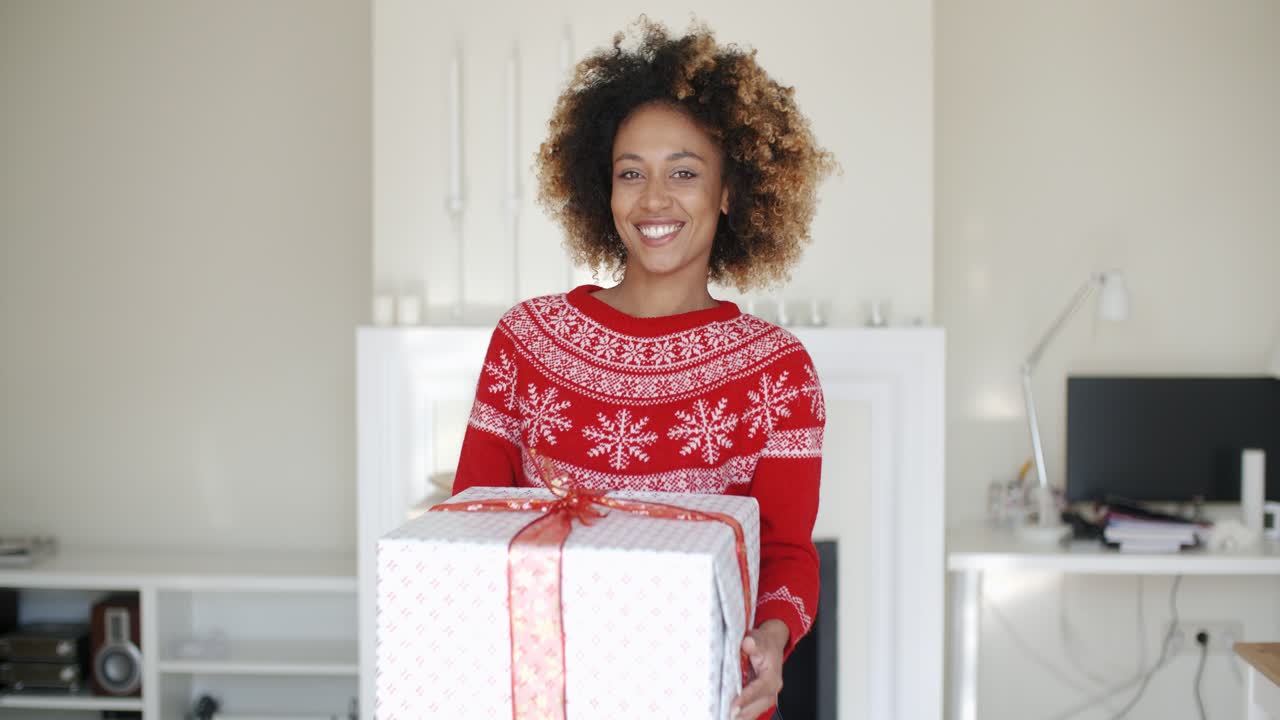 una chica feliz y sonriente con un corte de pelo afro sosteniendo un regalo