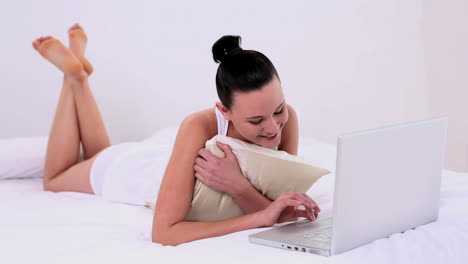 Happy-woman-using-her-notebook-lying-on-her-bed