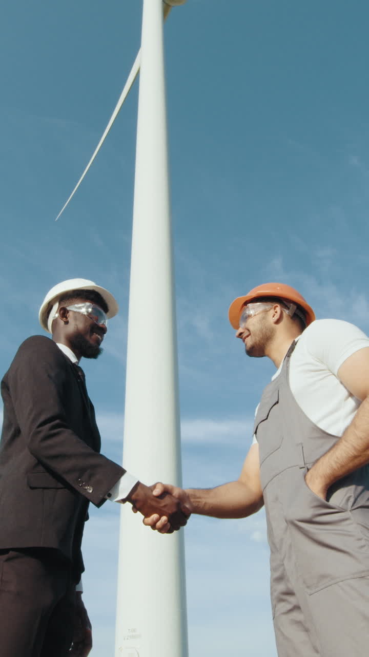 Engineers handshake by wind turbine