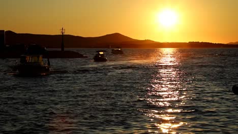 boats and yachts enter and exit marina at sunset in biograd in croatia