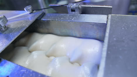 Milky creamy substance being rotated in the metal tank. Sweet products manufacturing at modern food factory. Close up.