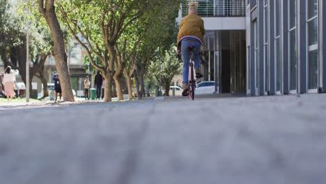 albino african american man with dreadlocks riding bike on street