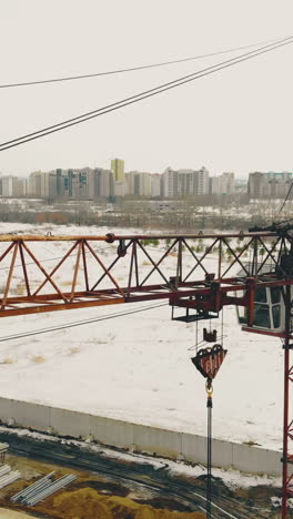 close high rusty construction cranes on building site by wasteland against distant city on nasty day aerial view