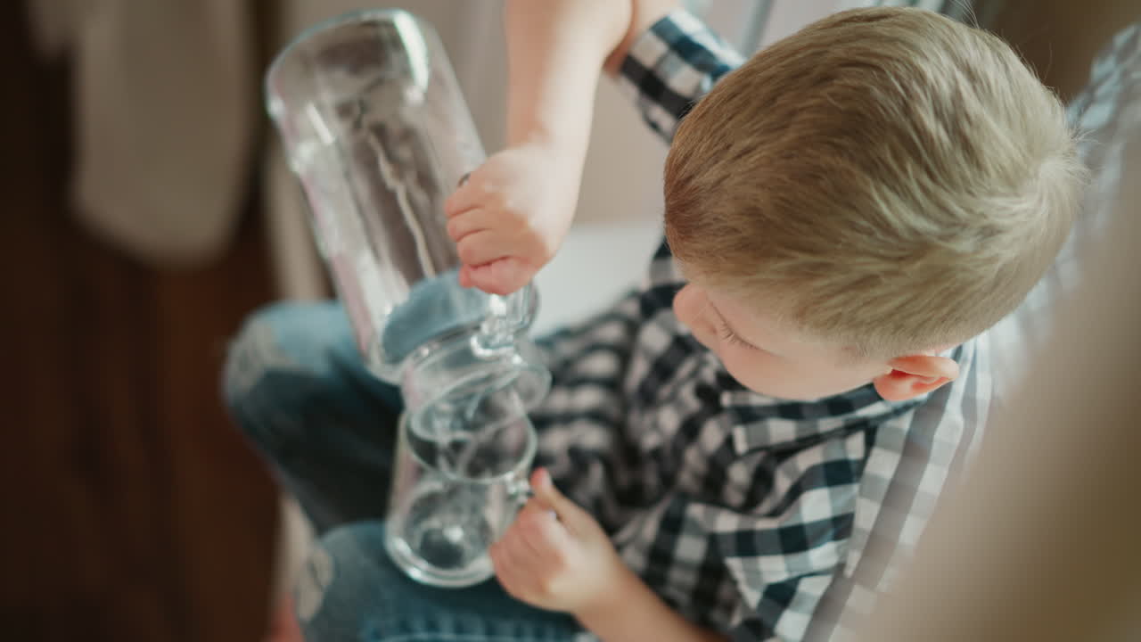 Child pouring water from jug into glass
