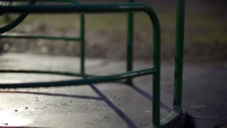 Wet carousel spinning at empty children's playground in city park on an autumn night.