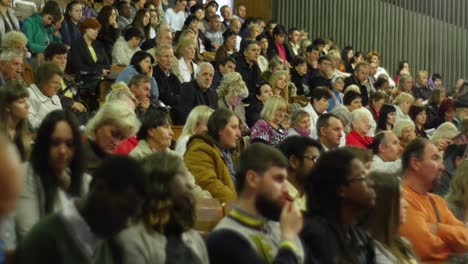 crowd of people to sitting and listening in a large hall