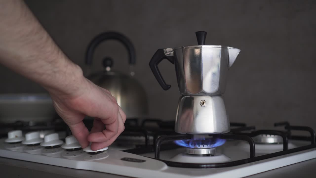 가스 밥솥에 있는 모카 커피 포트, 손으로 켜고, 푸른 불꽃의 근접 촬영 측면