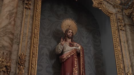 statue of jesus with a golden halo, dressed in red and white robes, in a richly adorned church setting