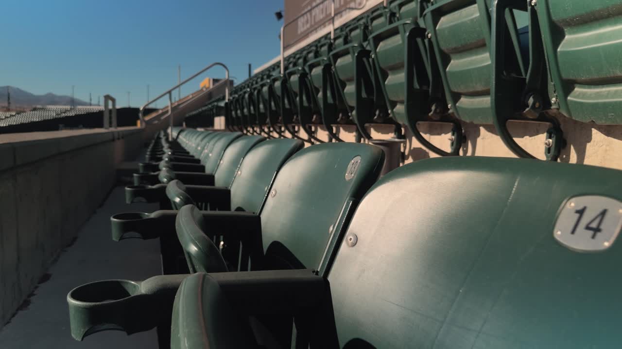 Deslize suave para frente passando por assentos e porta-copos vazios de estádio sob a luz clara do dia.