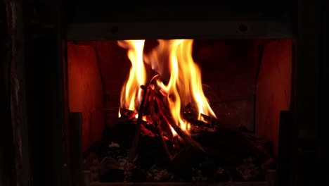 a wooden fire burning in a small fireplace with big flames and sparks. 4k shot.