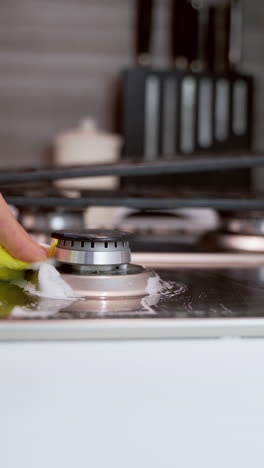 hand cleaning stove. close up of female hand cleaning the gas stove in kitchen