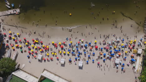 Overhead-aerial-footage-slowly-descending-of-Red-Beach,-Praia-Vermelha,-with-beach-goers-and-swimmers-on-a-hot-day-in-Rio-de-Janeiro