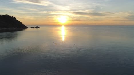 un hermoso amanecer sobre el océano con una persona paddleboarding en primer plano
