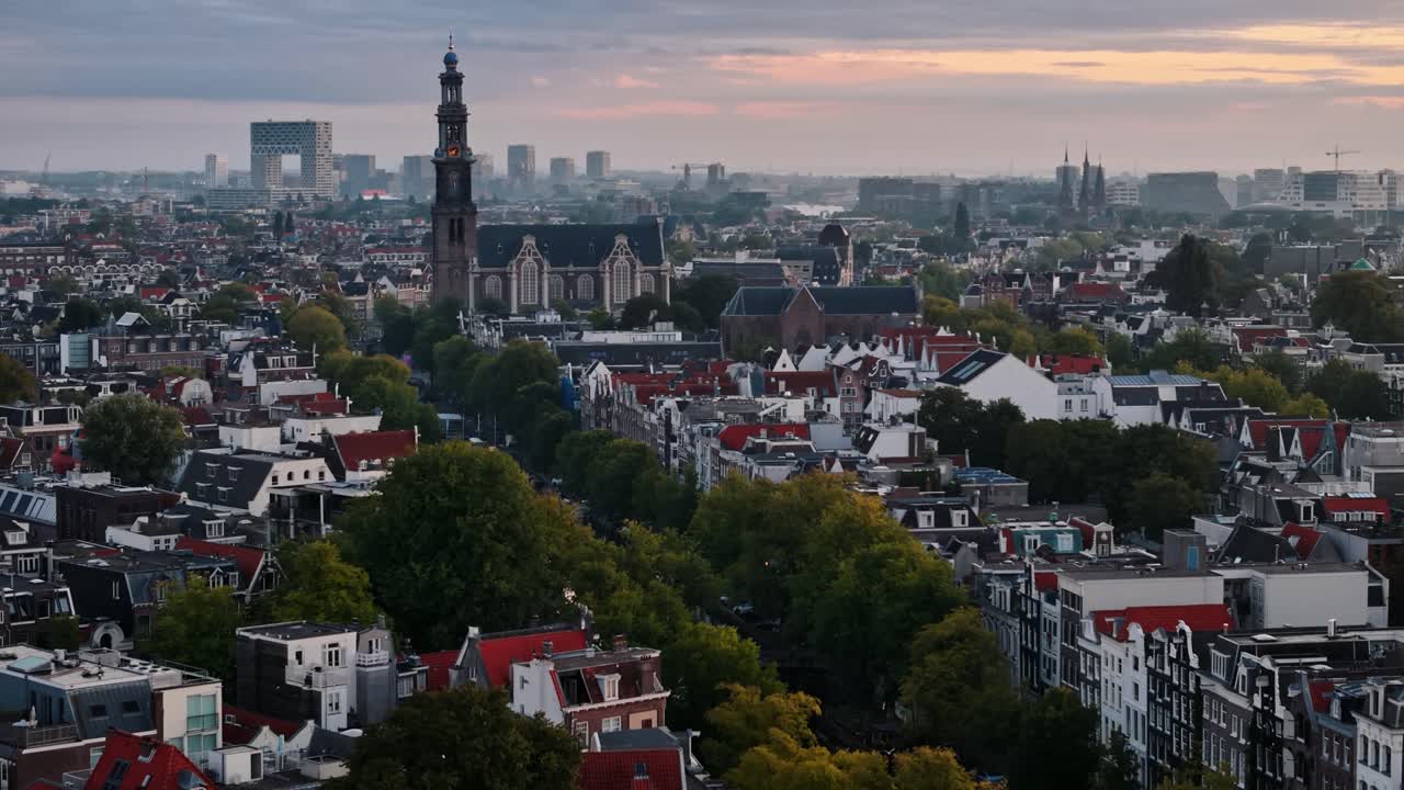 Circular drone tracking around church and canal during soft sunrise in Amsterdam, panoramic establish