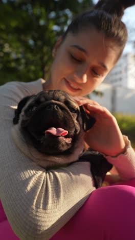 girl hugging a pug dog in a park