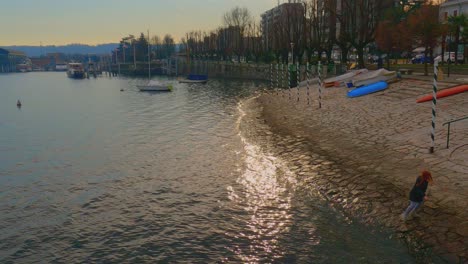 Niña-Con-El-Pelo-Rojo-Juega-En-La-Orilla-Del-Lago,-Arona-En-El-Lago-Maggiore