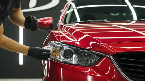 trabajador de servicio de automóviles aplicando nano recubrimiento en un detalle de automóvil.