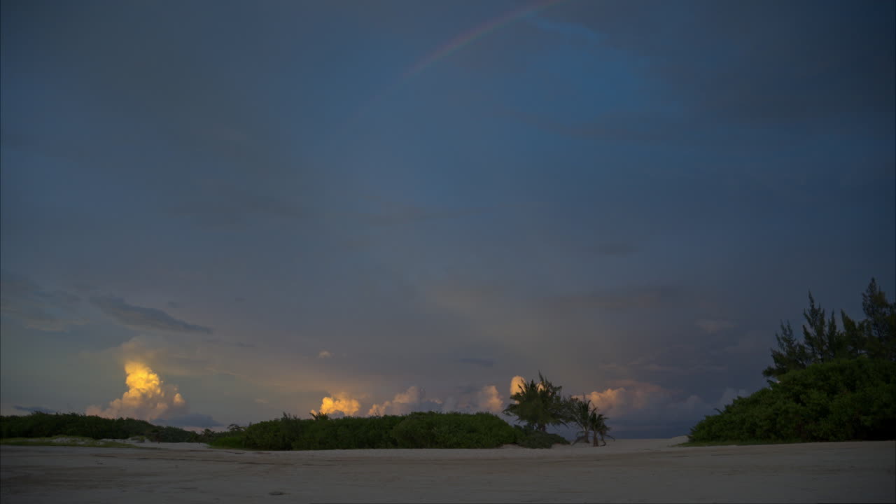 Matahari Terbenam yang Damai dengan Pelangi di Langit di Pantai Sepi Dekat Cancun, Meksiko