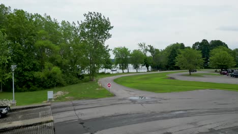 drone footage showcasing a winding road by a lake, surrounded by greenery