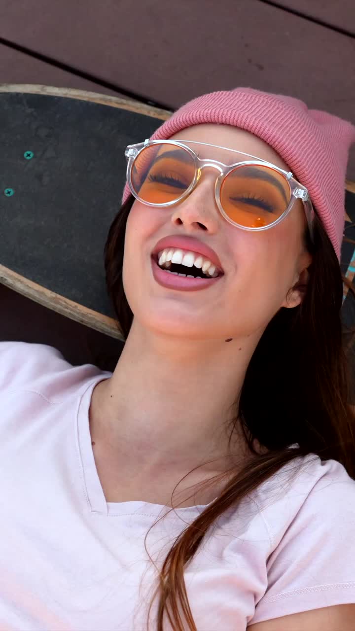 Woman with skateboard wearing sunglasses and beanie