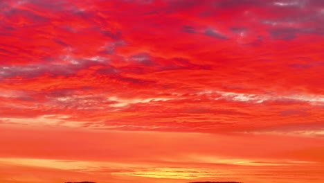 Drohnenaufnahmen-Eines-Spektakulären-Roten-Sonnenuntergangs,-Bei-Denen-Wir-Durch-Einen-Zoom-Die-Leuchtend-Rötlichen-Farben-Sehen,-Die-Auf-Die-Wolken-Am-Himmel-Gemalt-Sind