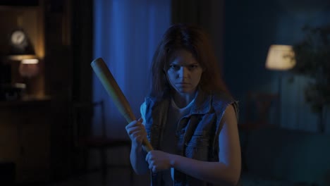 girl in casual with angry face expression looking at the camera holding baseball bat ready to fight