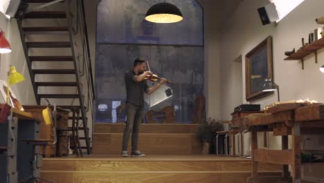 un luthier barbudo adulto tocando un violín hecho a mano