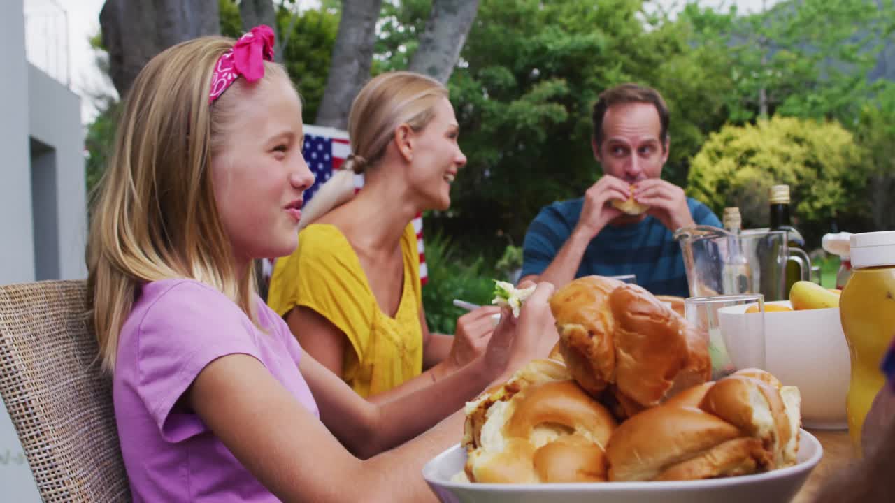 sonriente chica caucásica comiendo en la celebración familiar comida en el jardín